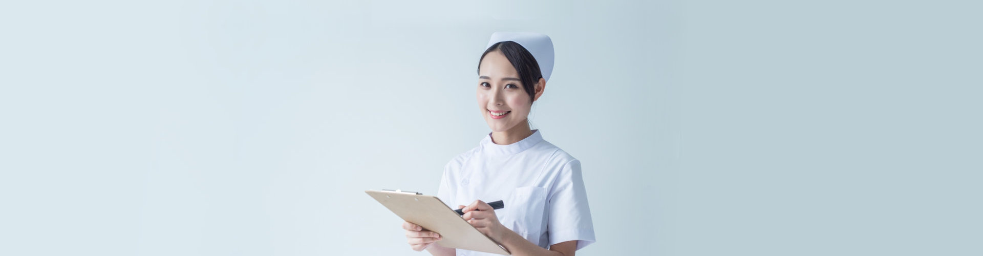 nurse smiling while writing on her clipboard