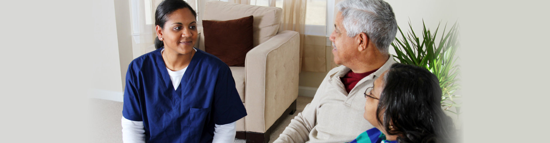 nurse or caregiver talking to elderly couple